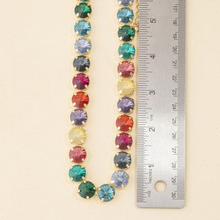 Multicolor glass stone necklace laid beside ruler